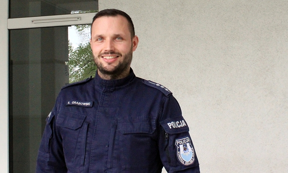 umundurowany policjant stoi pod budynkiem Komendy Miejskiej Policji w Toruniu