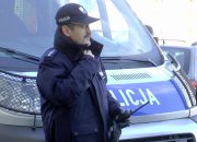 Zdjęcie przedstawiające funkcjonariusza Policji stojącego przy radiowozie służbowym