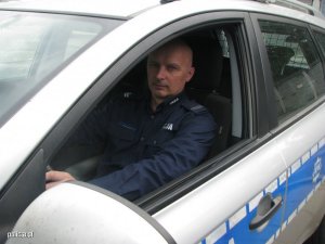 Zdjęcie przedstawiające policjanta siedzącego w radiowozie służbowym