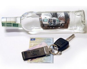 Zdjęcie przedstawiające butelkę alkoholu oraz kluczyki od pojazdu
