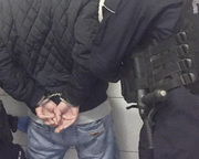 Zdjęcie przedstawiające plecy mężczyzny w ciemniej kurtce ze skutymi z tyłu rękami.
