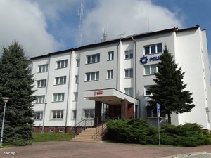 Zdjęcie frontu siedziby Komendy Powiatowej Policji w Ropczycach. Budynek w kolorze szarym.