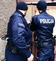 zdjęcie dwóch odwróconych, umundurowanych policjantów na tle narożnika budynku