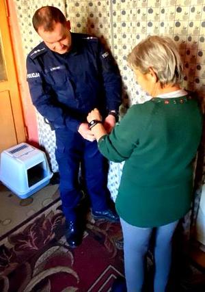 Policjant zapinający opaskę na ręku starszej kobiety