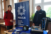 Zdjęcie przedstawiającego sylwetki umundurowanego policjanta oraz młodego mężczyzny między którymi widoczny jest baner koloru granatowego z logiem Policja.