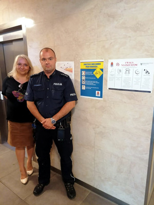 Zdjęcie umundurowanego policjanta i uśmiechniętej kobiety na klatce schodowej.