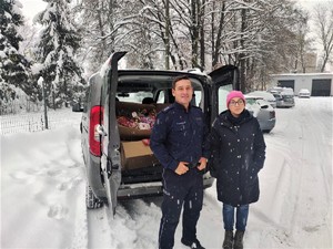 Policjanci przy aucie wypełnionych słodyczami i darami dla potrzebujących dzieci