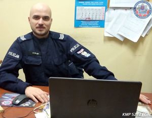 Umundurowany policjant siedzący za biurkiem.