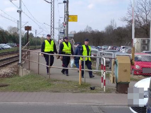Zejście z peronu kolejowego z oddali, widocznych trzech umundurowanych mężczyzn w żółtych kamizelkach.