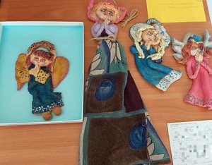 Leżące na stole kartki pocztowe oraz pacynki w kształcie aniołów