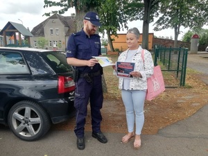 Kobieta otrzymująca od policjanta broszury informacyjne
