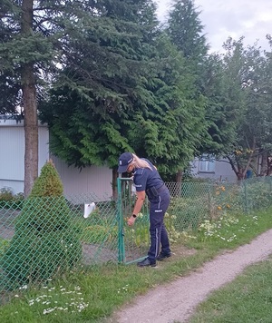Policjantka przy furtce na terenie ogródków działkowych