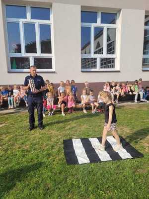 Dzielnicowy przedstawiający dzieciom zapewnienie bezpieczeństwa w trakcie drogi do szkoły.