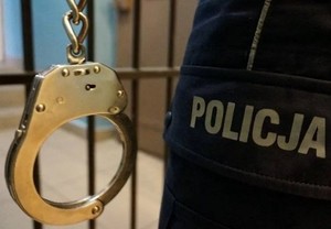 Zdjęcie przedstawiające nogawkę munduru z napisem Policja i dłoń trzymającą kajdanki na tle krat aresztu.