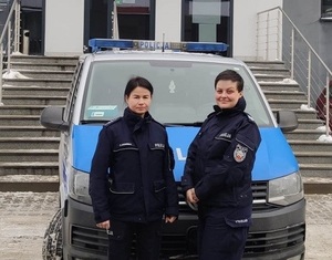 Dwie policjantki na tle radiowozu typu bus stojącego przed dużymi schodami