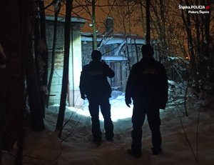 Dwaj policjanci w zimowej scenerii nocnej w rejonie starych pustostanów