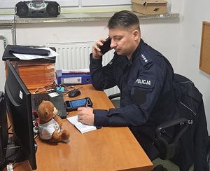 Policjant siedzący w pokoju biurowym z telefonem przy uchu