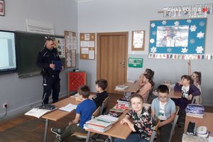 Sala lekcyjna wypełniona dziećmi dla których pogadankę prowadzi umundurowany policjant