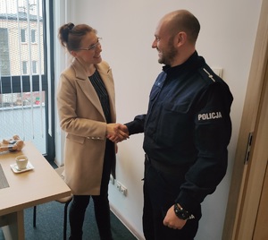 Uśmiechnięta kobieta ściskająca dłoń policjantowi