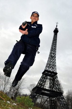 Umundurowana policjantka oddająca skok na tle miniatury wieży Eiffla