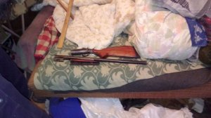 Zdjęcie zdemontowanej strzelby myśliwskiej ukrytej w pościeli łóżka.