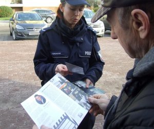 Zdjęcie przedstawiającą dzielnicową przekazującą ulotkę informacyjną obywatelowi