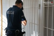 Zdjęcie przedstawiające policjanta stojącego przy drzwiach pomieszczenia dla osób zatrzymanych