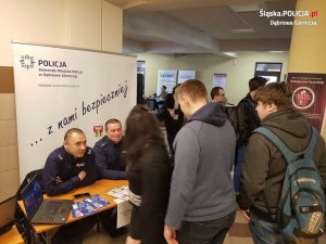 Zdjęcie przedstawiające dwójkę dzielnicowych siedzących przy stole na targach pracy, którzy promowali pracę w Policji