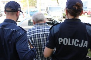 Zdjęcie przedstawiające zatrzymanego prowadzonego przez dwójkę policjantów