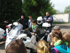 Zdjęcie przedstawiające policjanta wraz z dziećmi, którzy stoją obok policyjnego motocykla służbowego