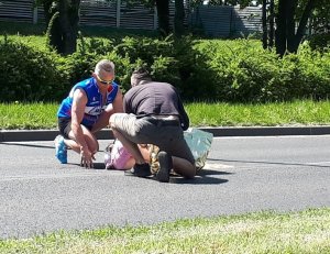 Zdjęcie przedstawiające osoby udzielające pomocy poszkodowanemu na drodze