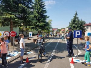 Zdjęcie przedstawiające dzielnicowego podczas nauki dzieci bezpiecznej jazdy na rowerze