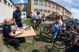 Zdjęcie przedstawiające dwójkę policjantów podczas znakowania rowerów na festynie