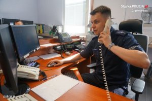 Zdjęcie przedstawiające policjanta na stanowisku dyżurnego, przyjmującego zgłoszenie telefoniczne