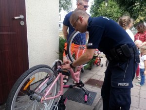 Zdjęcie przedstawiające policjanta znakującego rower