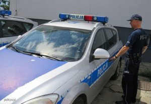 Zdjęcie przedstawiające policjanta otwierającego radiowóz policyjny