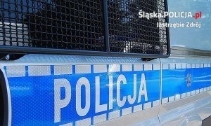 Zdjęcie przedstawiające napis Policja na drzewiach radiowozu