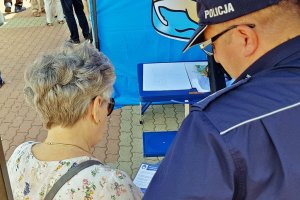 Zdjęcie przedstawiające policjanta przekazującego ulotkę starszej kobiecie