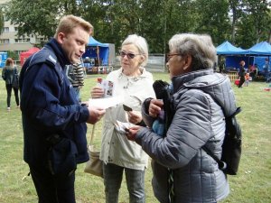 Zdjęcie przedstawiające policjanta przekazującego seniorom ulotki