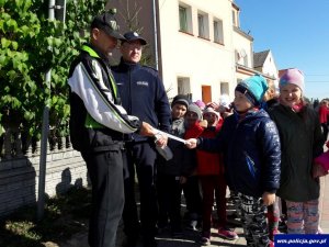 Zdjęcie przedstawiające policjanta rozdającego opaski odblaskowe