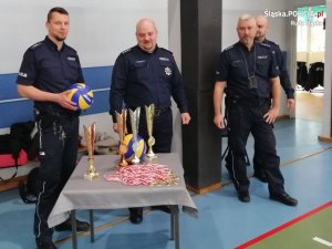 Zdjęcie przedstawiające policjantów stojących przy pucharach