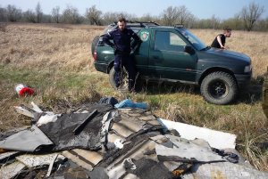 Zdjęcie przedstawiające policjanta stojącego przy stercie śmieci