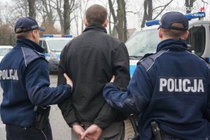 Zdjęcie przedstawiające policjantów stojących z zatrzymanym skutym w kajdanki