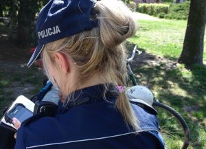 Zdjęcie przedstawiające policjantkę dokonującą sprawdzenia na urządzeniu mobilnym