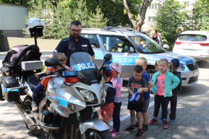 Zdjęcie przedstawiające policjanta prezentującego dzieciom motocykl policyjny