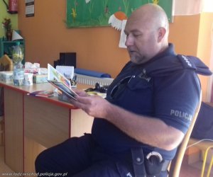 Zdjęcie przedstawiające policjanta czytającego książkę