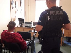 Zdjęcie przedstawiające policjanta stojącego przy zatrzymanym