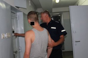 Zdjęcie przedstawiające policjanta stojącego z zatrzymanym