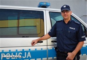 Zdjęcie przedstawiające policjanta stojącego przy radiowozie