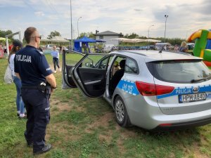 Zdjęcie przedstawiające policjanta stojącego przy radiowozie